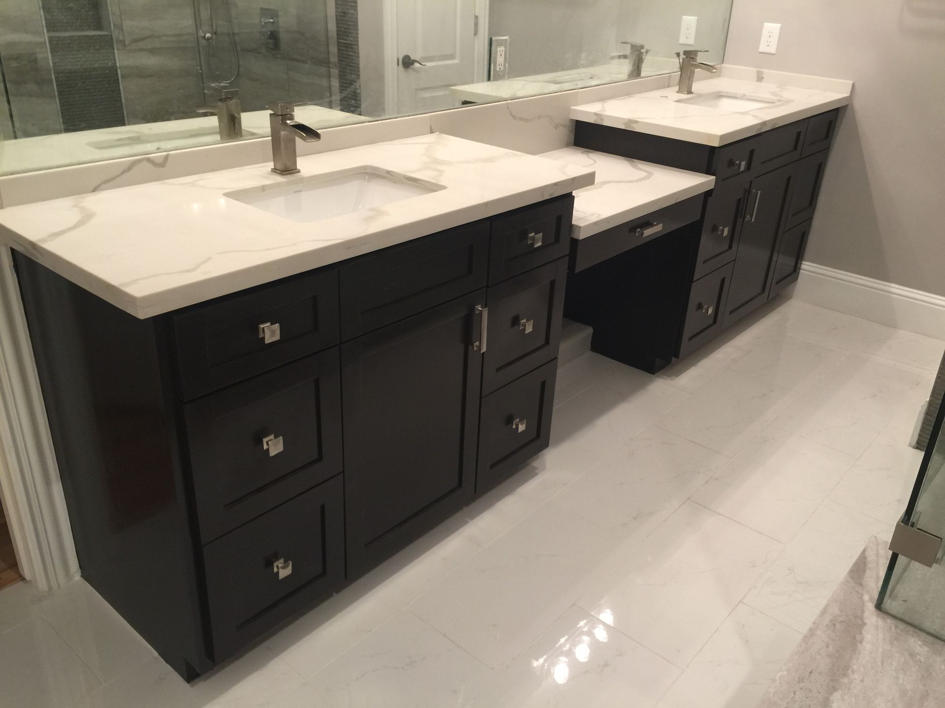 Dark brown bathroom vanity with white countertop, two sinks, and white tile floor.