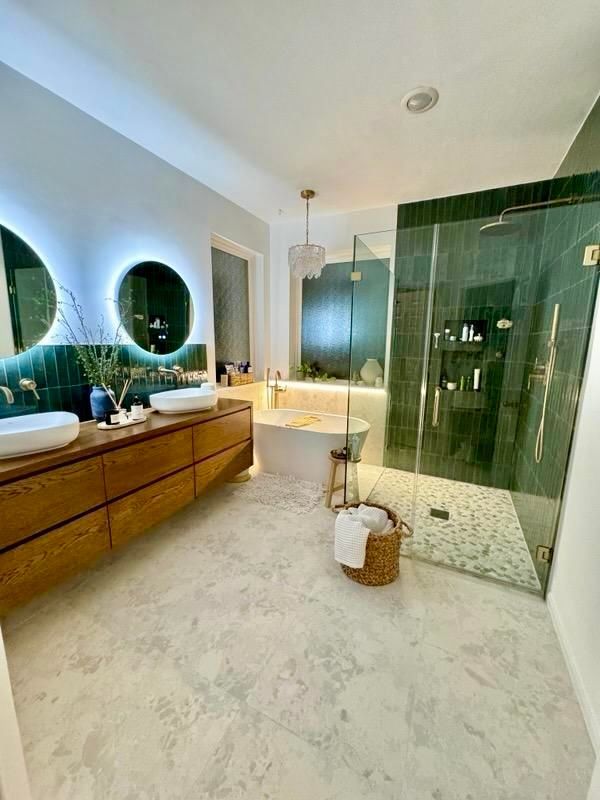 Luxurious bathroom with wood vanity, green tile accents, and a glass shower.