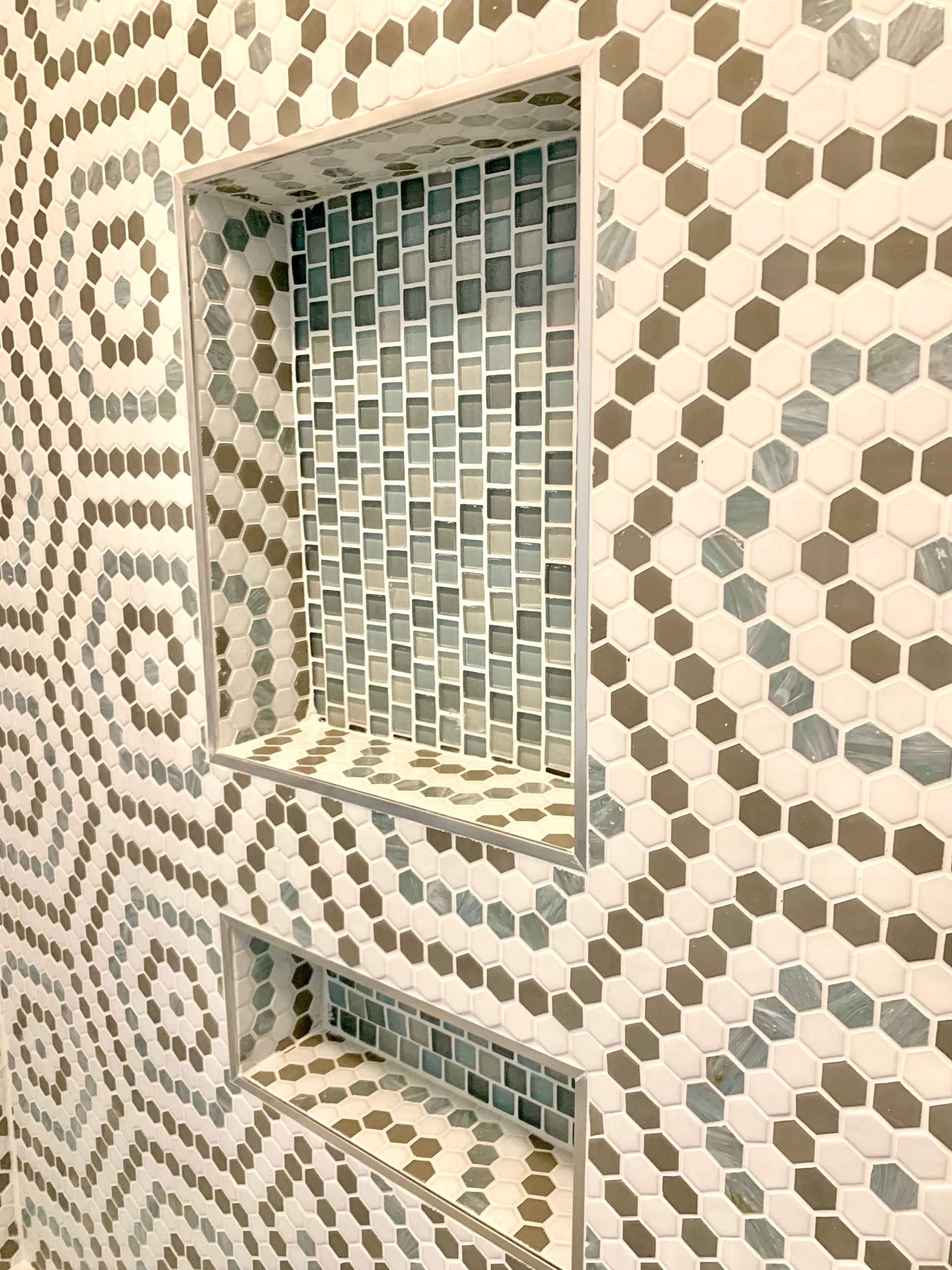 Bathroom shower wall with hexagon and mosaic tile, with built-in shelf.