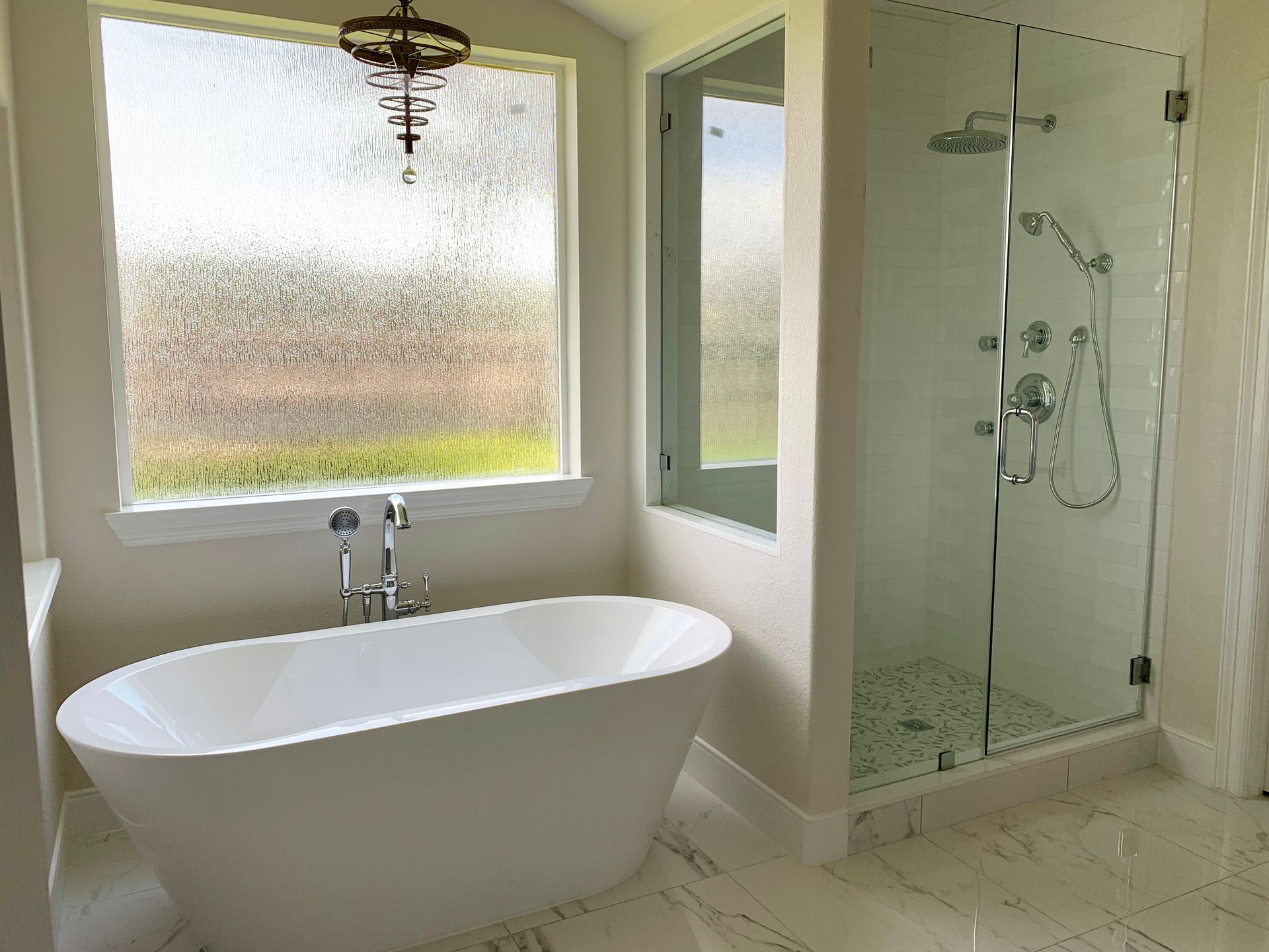 Modern bathroom with a white freestanding tub, glass shower, and textured window.