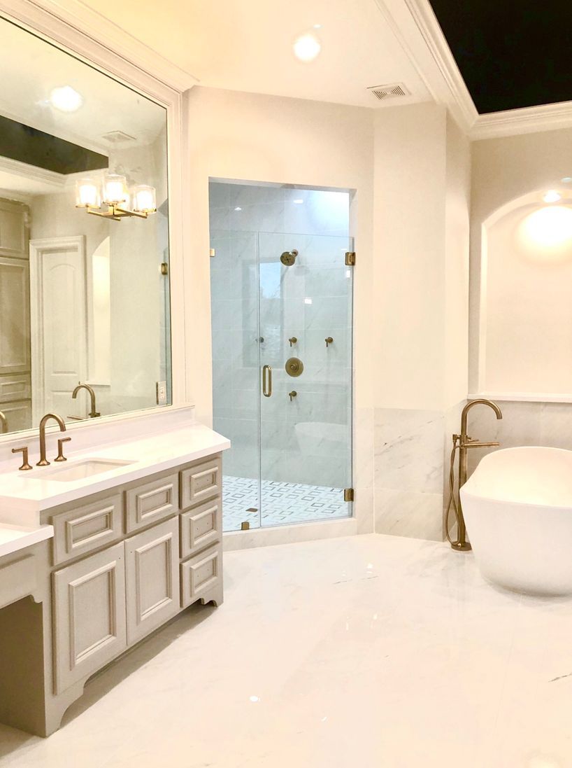 Luxurious bathroom with marble floors, a glass shower, and a white soaking tub.