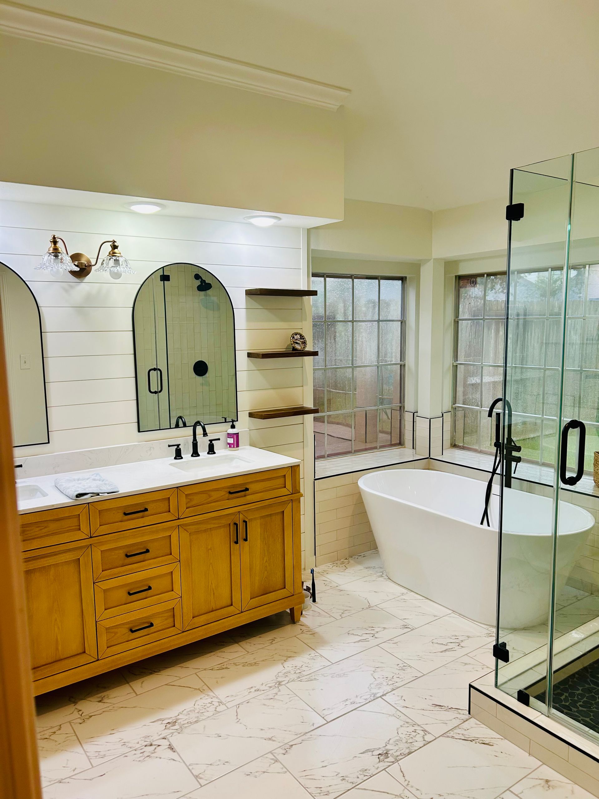 Bathroom with a wooden vanity, a free-standing bathtub, and a glass shower enclosure.
