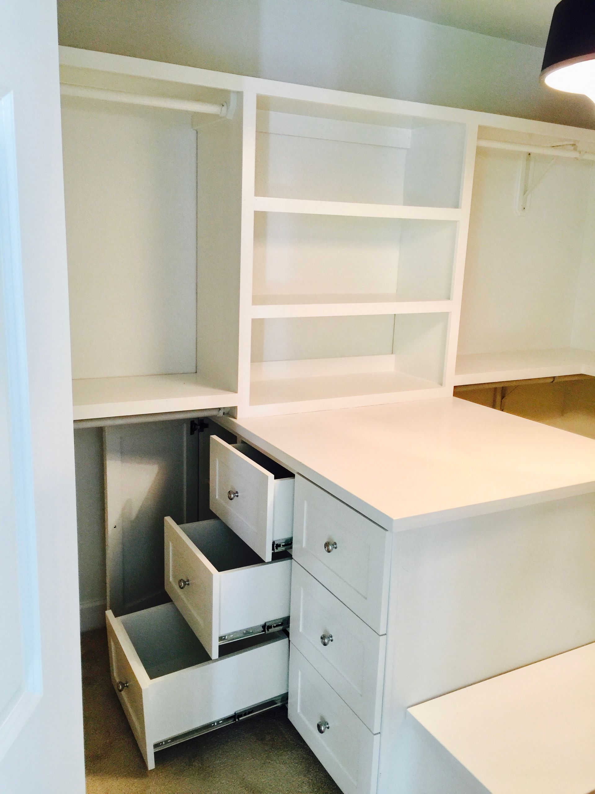 White custom closet with drawers, shelves, and hanging rods.