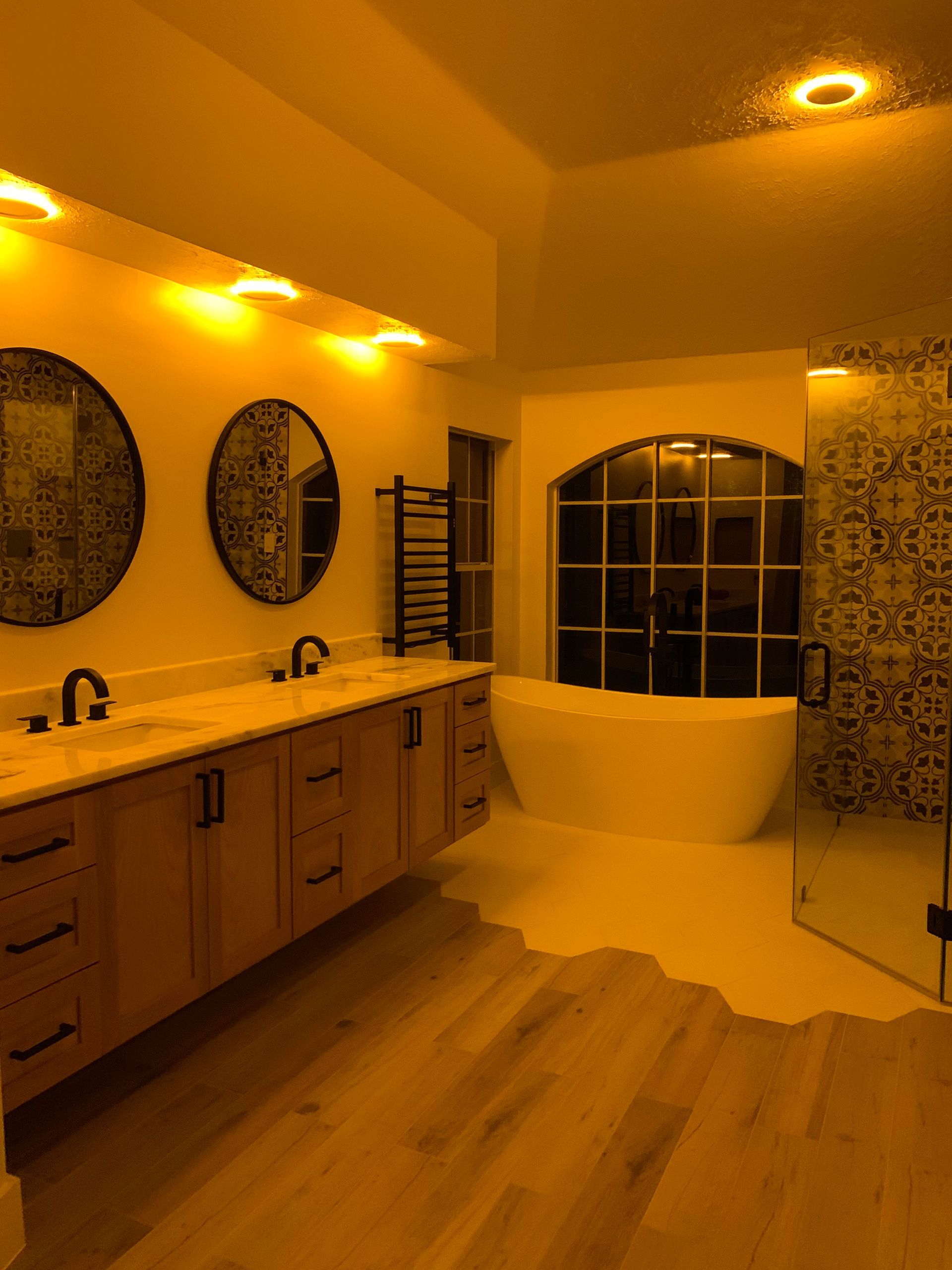 Bathroom with dual vanity, freestanding tub, and shower; wood and tile.