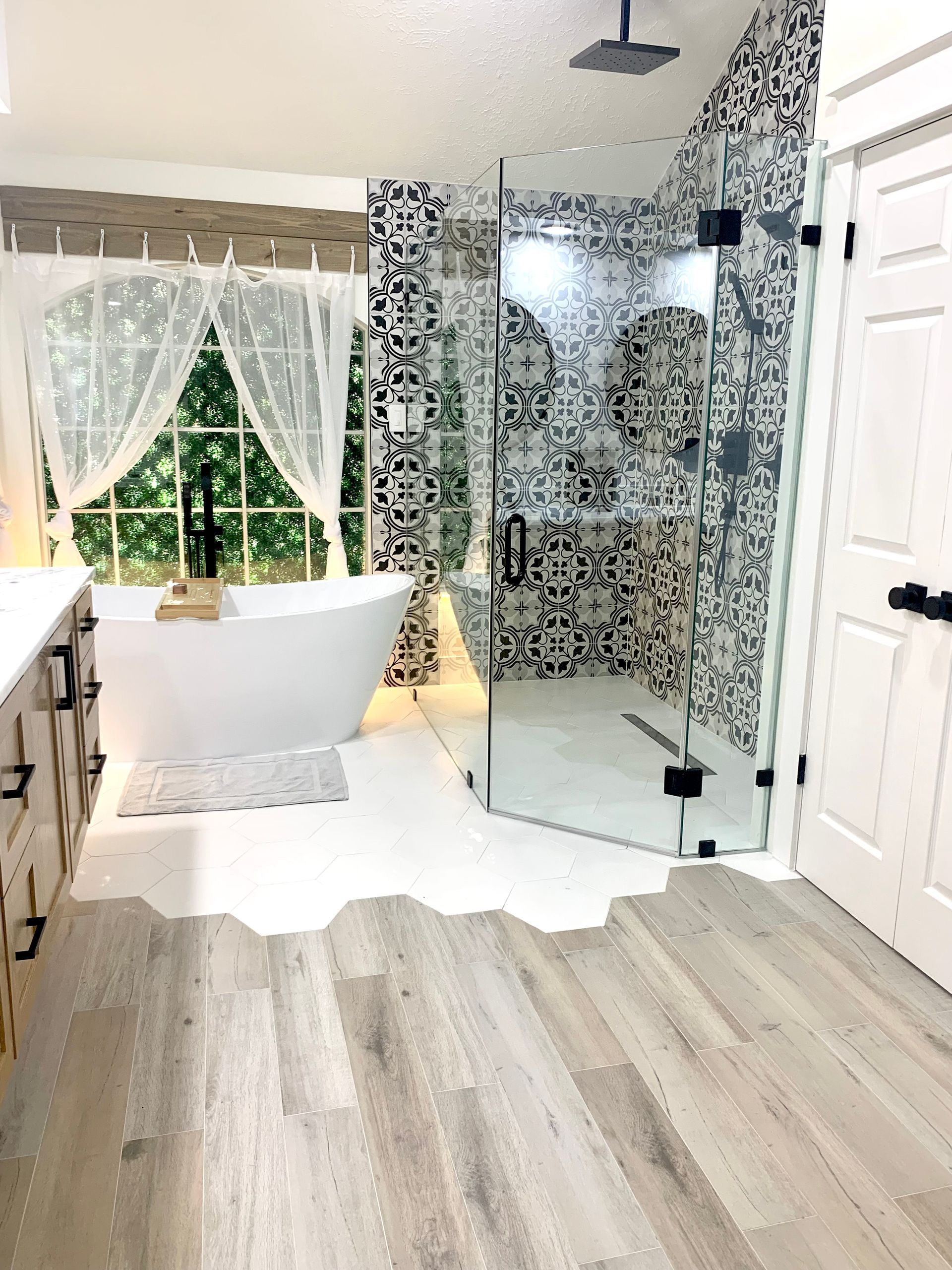 Modern bathroom with free-standing tub, glass shower, and mosaic tile wall.  