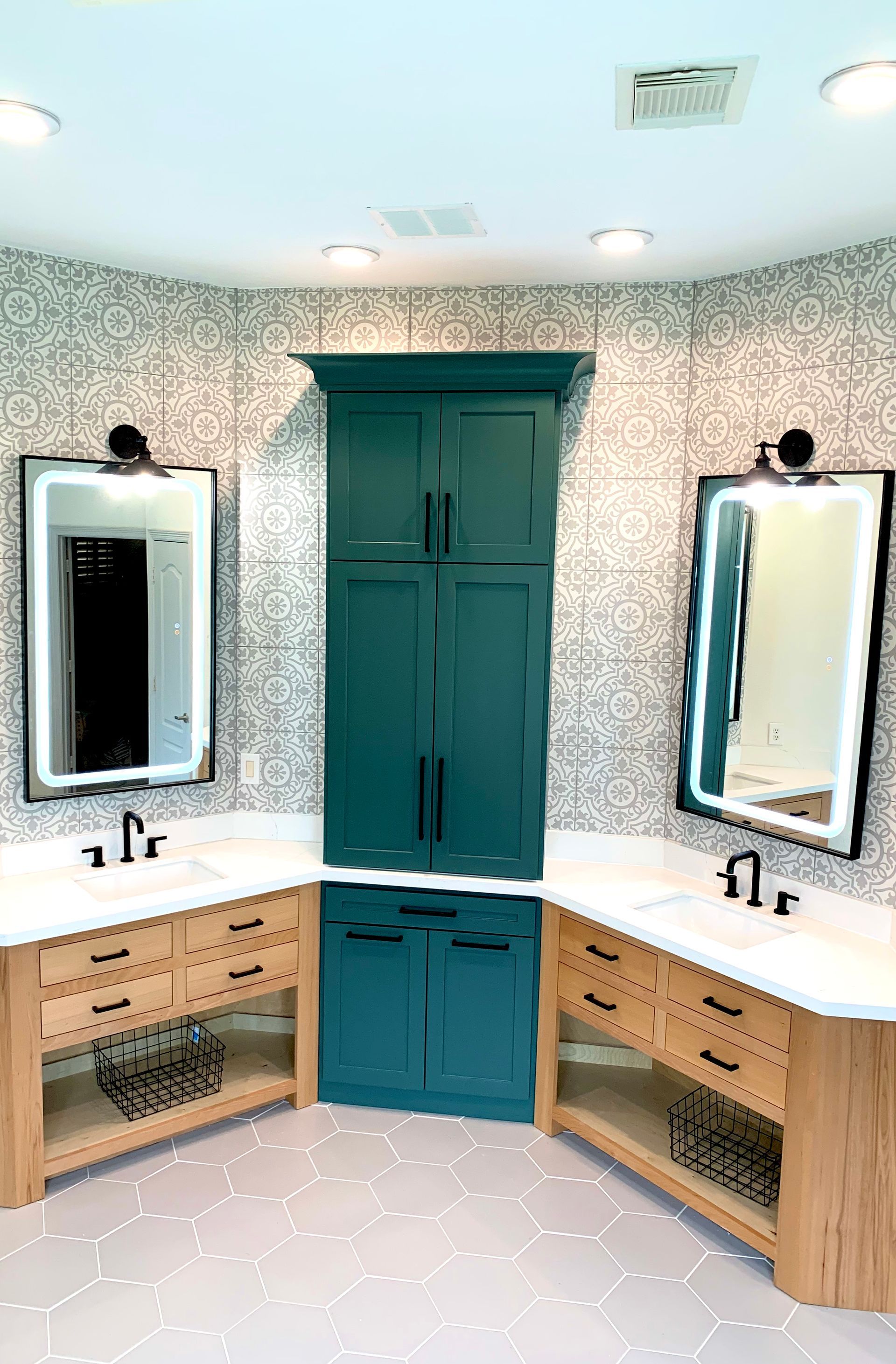 Modern bathroom with teal cabinet, wood vanities, and patterned wallpaper.