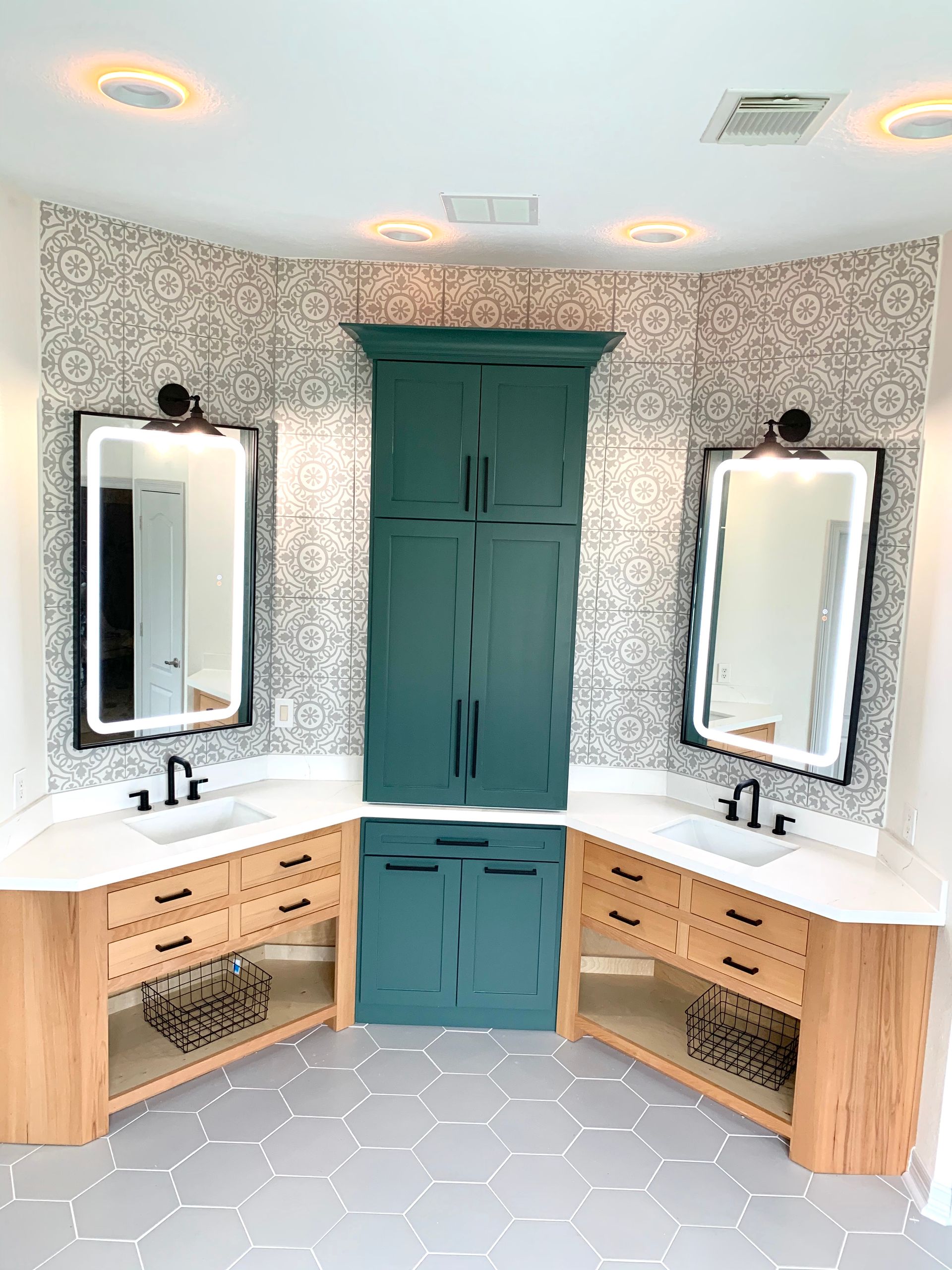 Bathroom with two sinks, a central cabinet, and hexagon tile floor. 