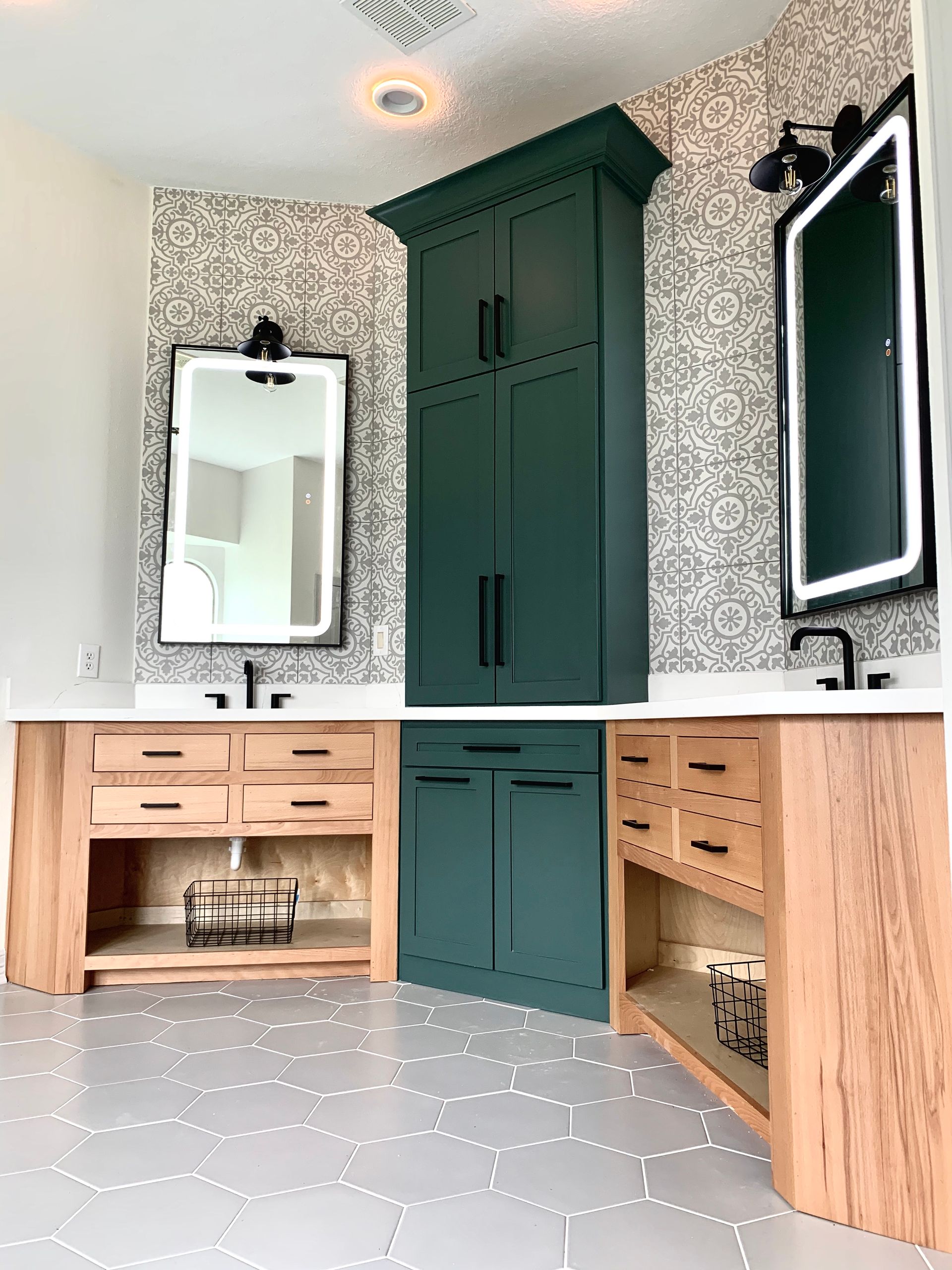 Bathroom with green cabinet, wood vanities, black mirrors, and patterned wallpaper.