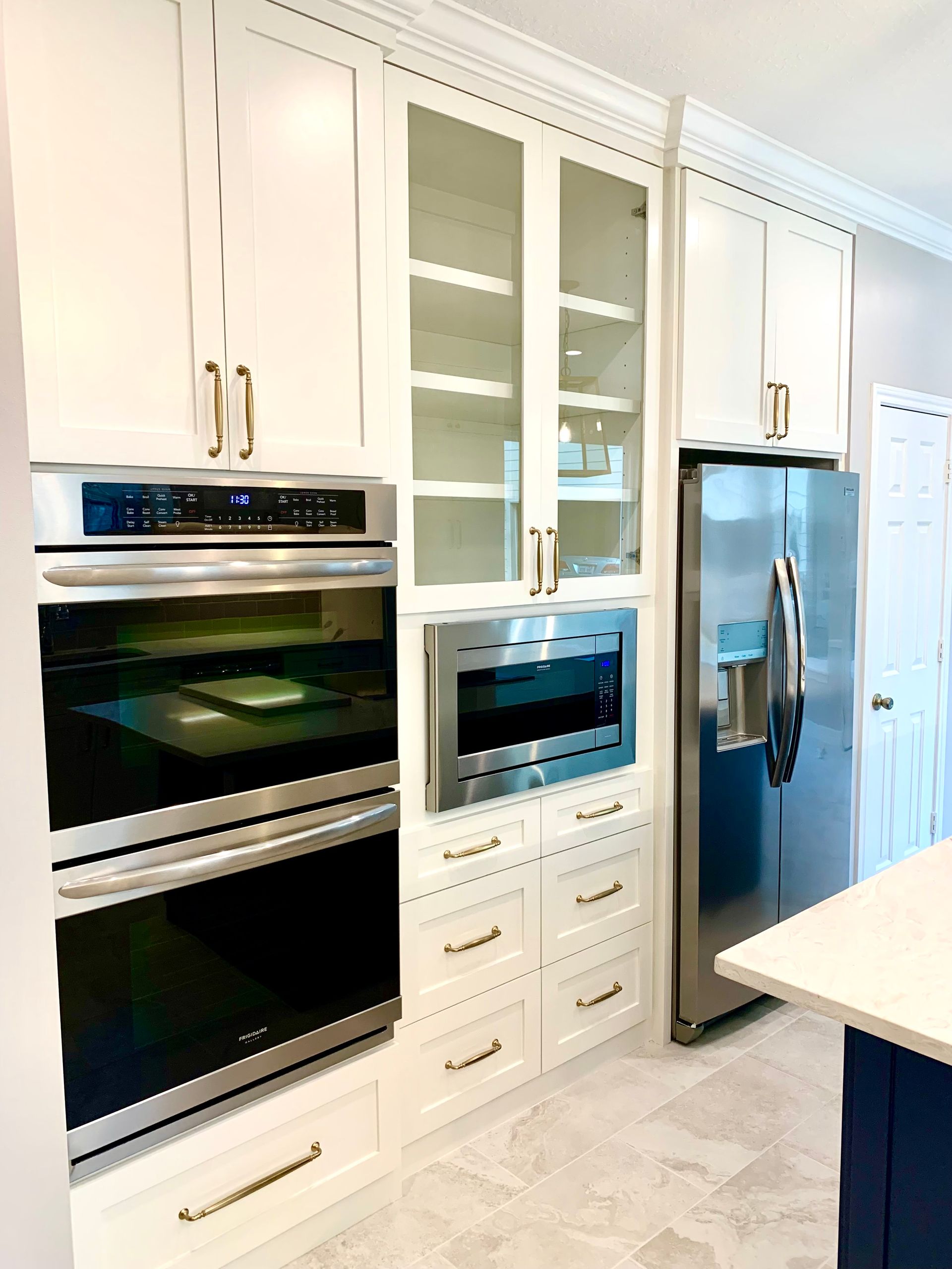 White kitchen cabinets with built-in appliances, including an oven, microwave, and refrigerator.