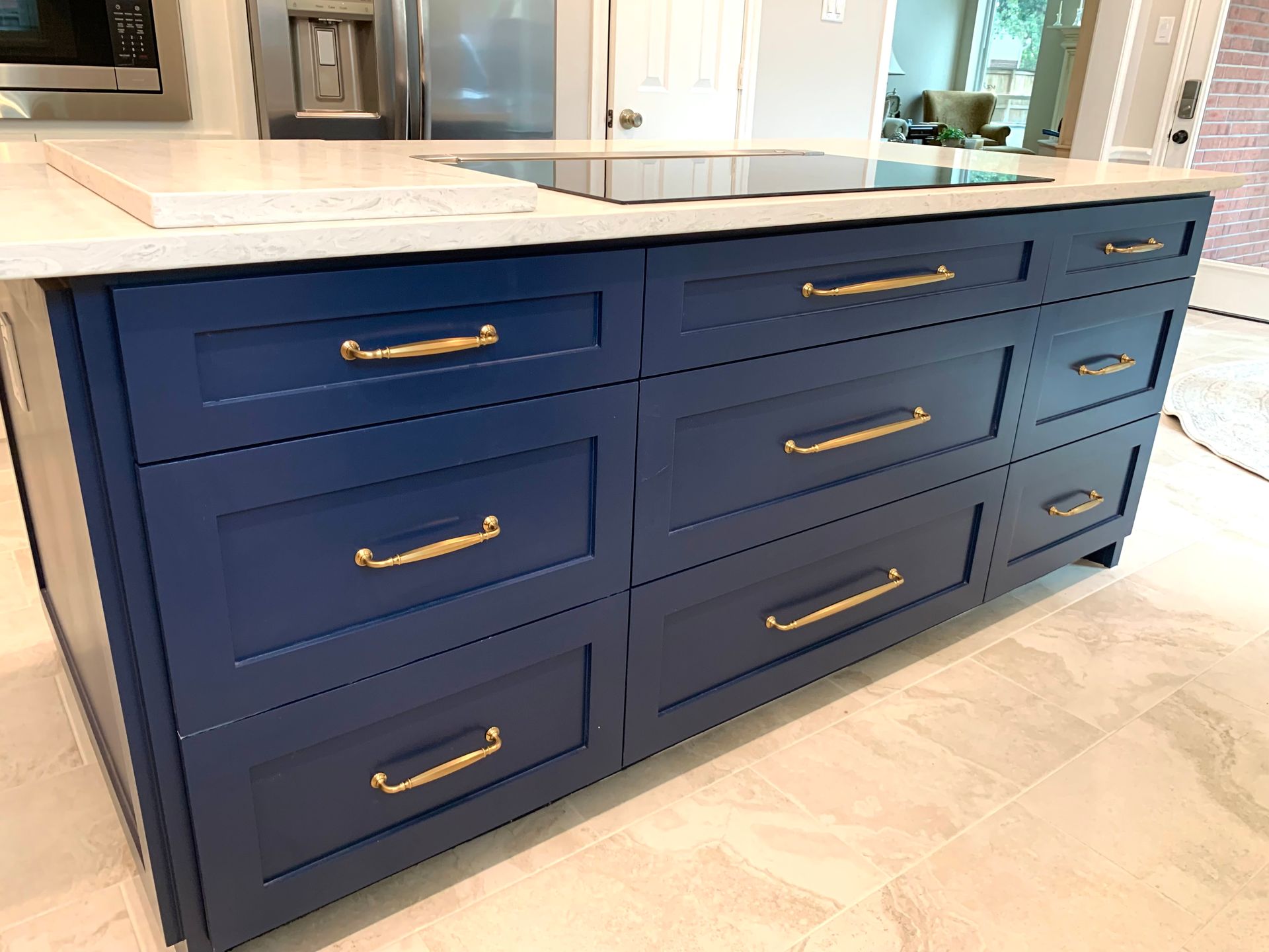 Blue kitchen island with gold hardware and cooktop.