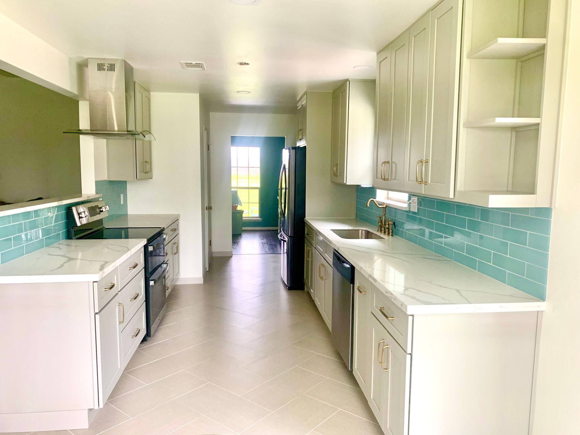 Modern kitchen with gray cabinets, marble countertops, and turquoise backsplash.
