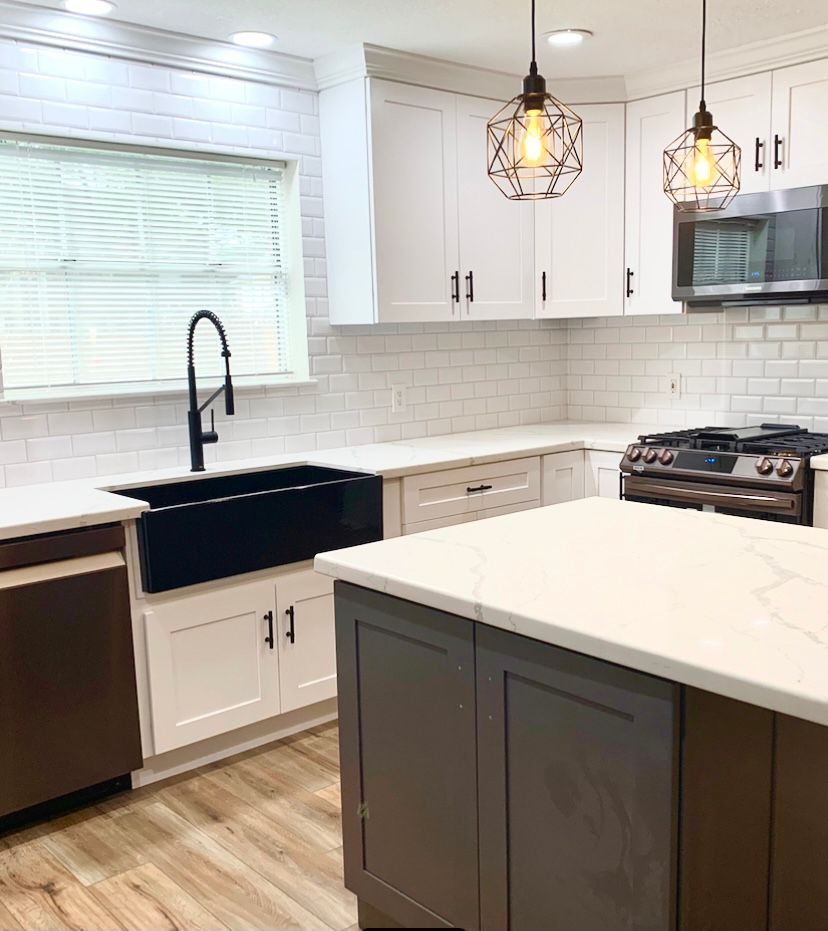 Modern kitchen with white cabinets, dark island, and black accents, light countertops.