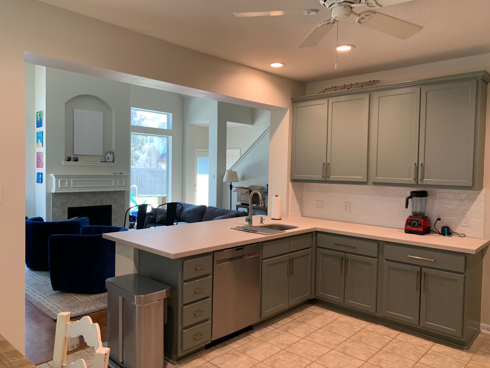 Kitchen with gray cabinets, island, and open view to living room. 