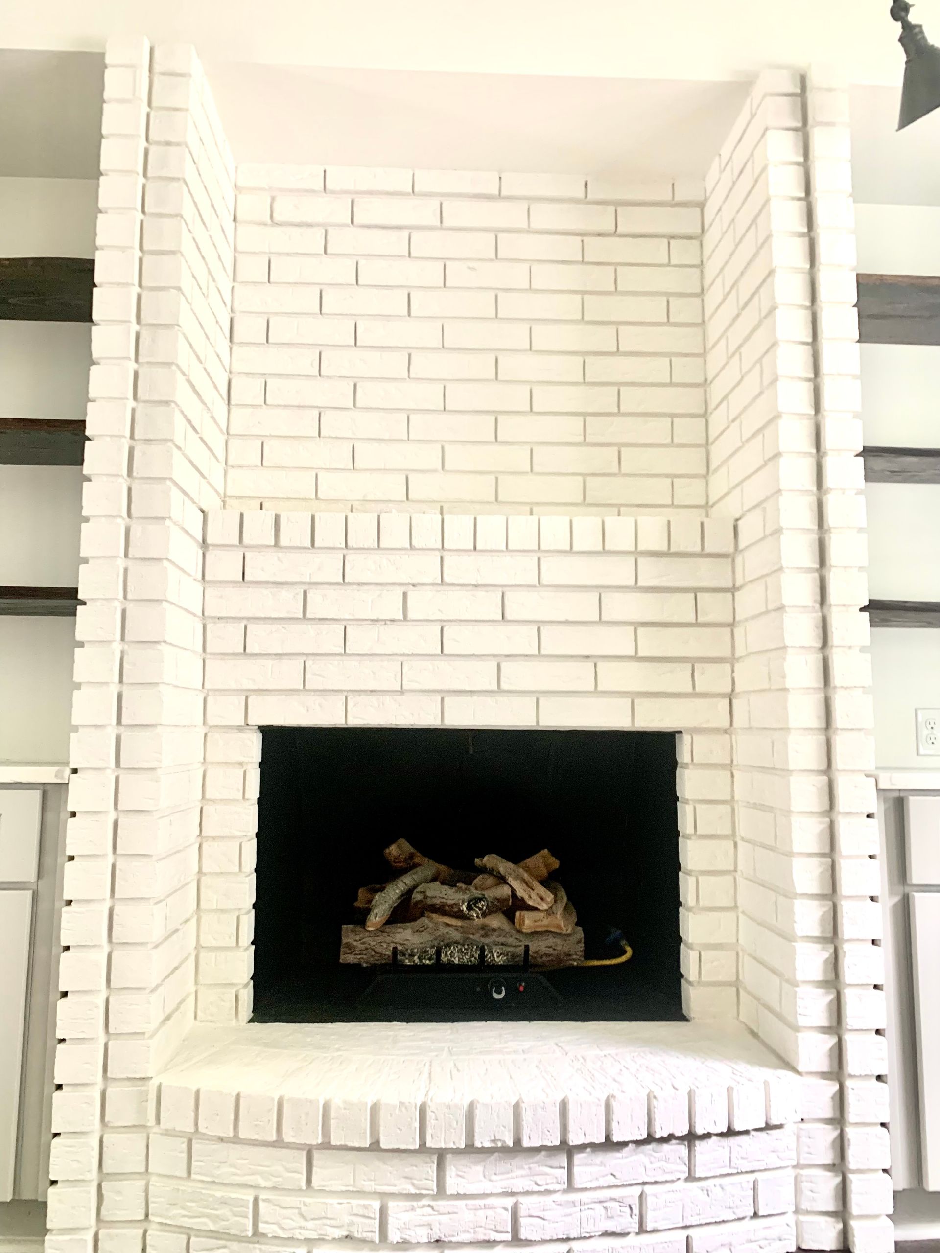 White brick fireplace with built-in shelves on either side.