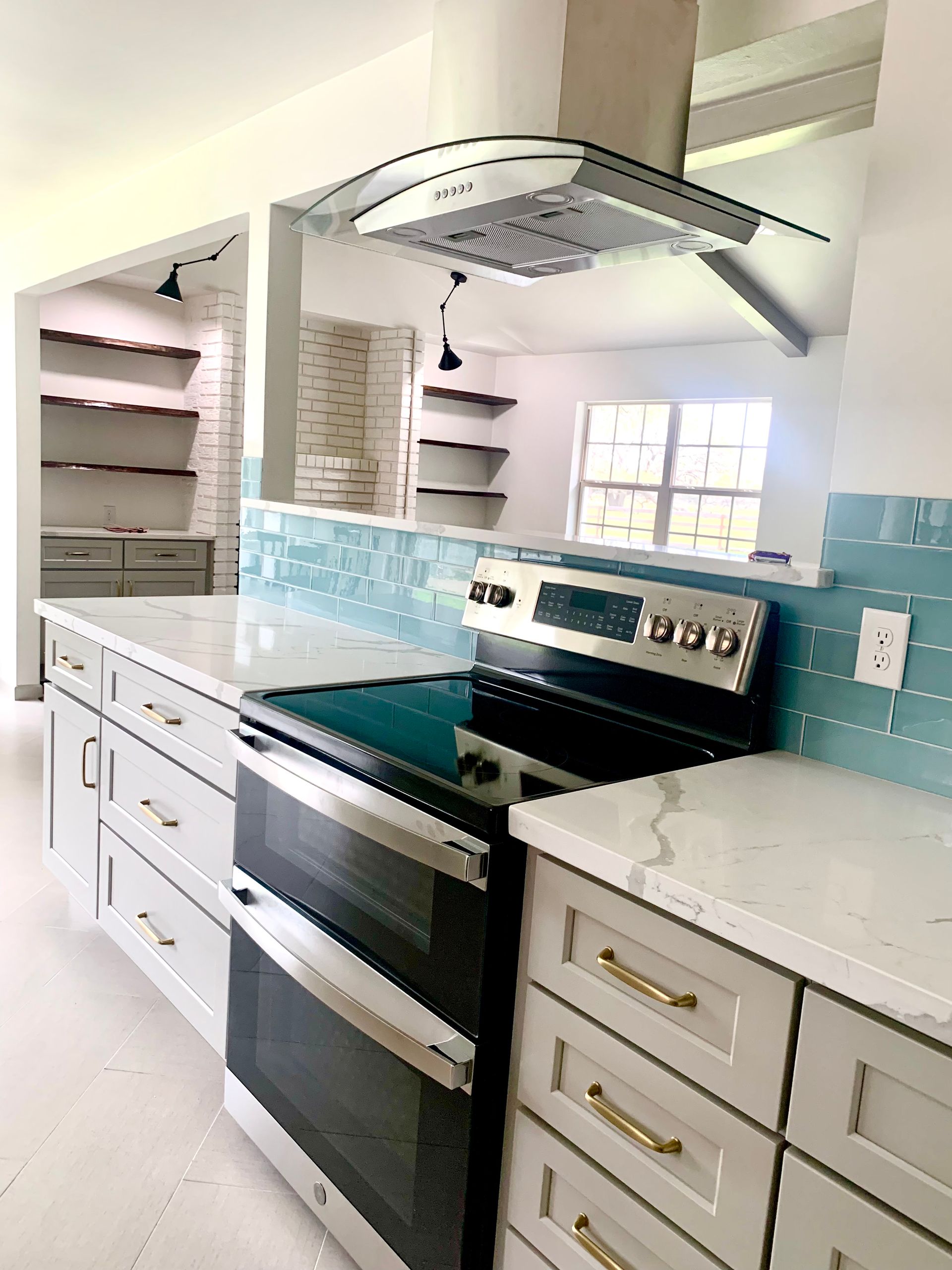 Modern kitchen with stainless steel appliances, light blue backsplash, white countertops, and gray cabinets.