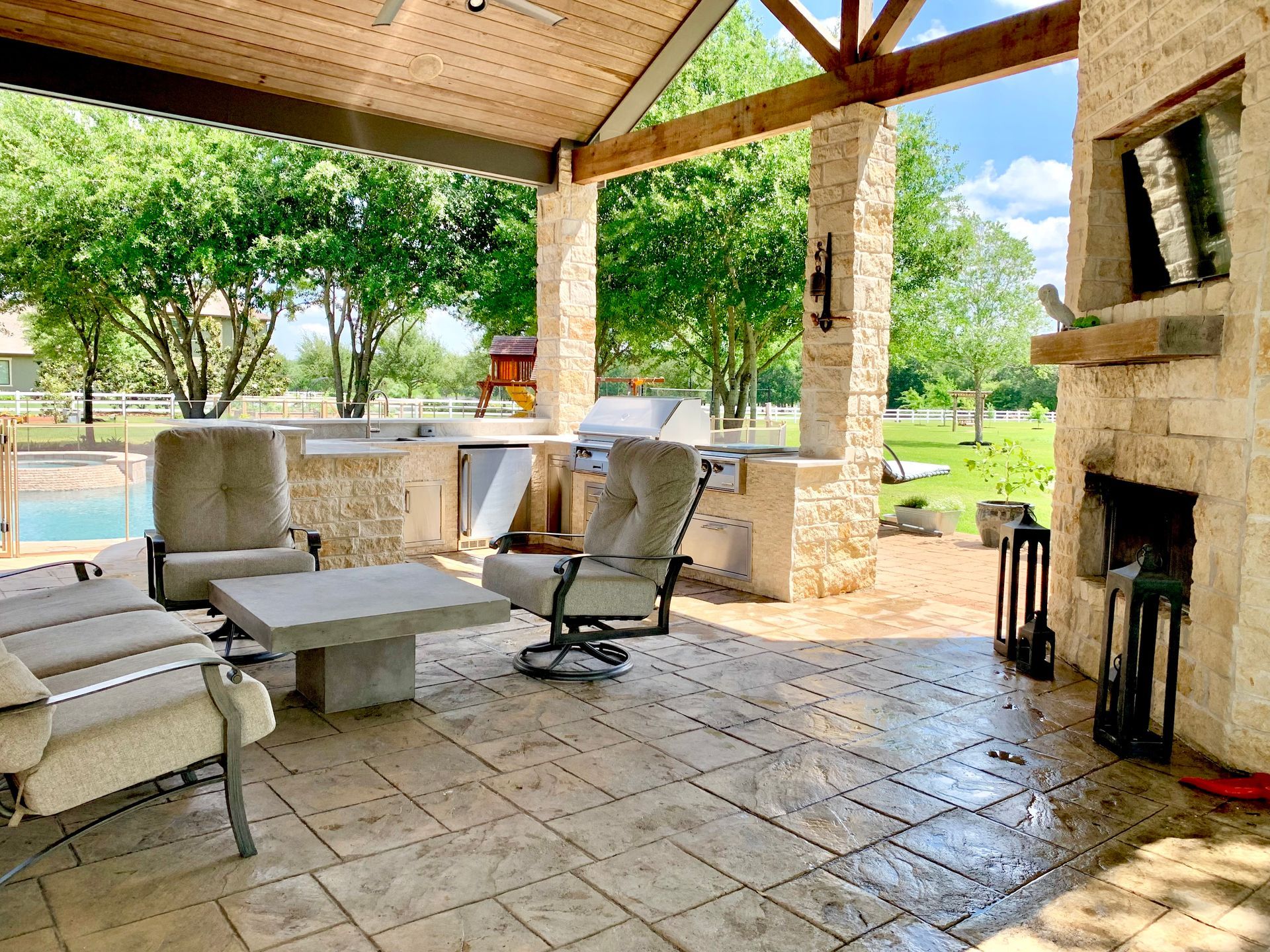 Outdoor patio with seating, fireplace, and built-in grill under a covered roof.
