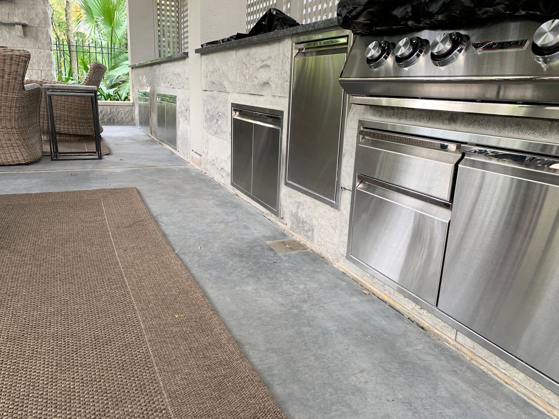 Outdoor kitchen with stainless steel appliances set into a stone countertop. 
