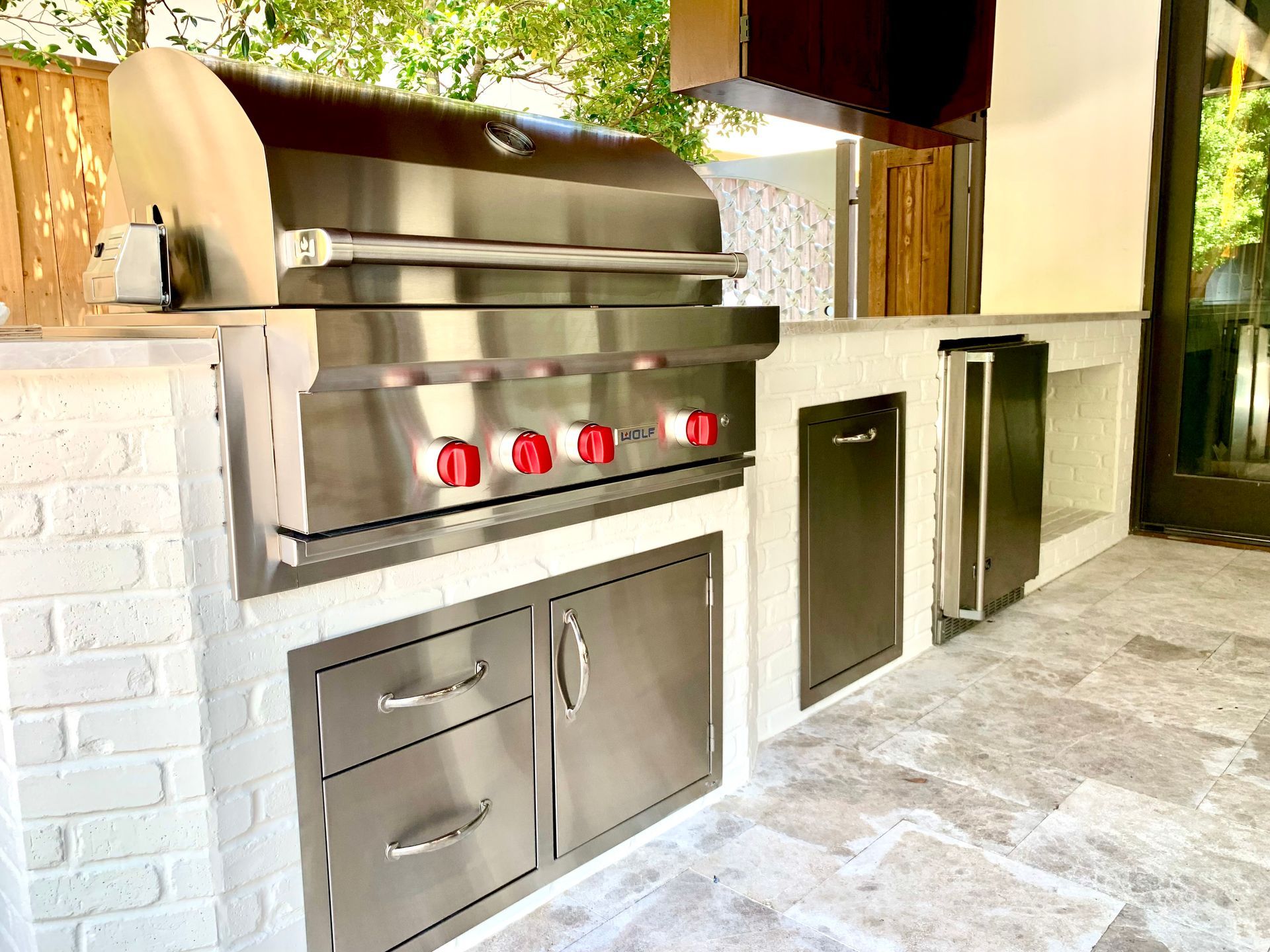 Outdoor kitchen with stainless steel grill, cabinets, and a built-in cooler.