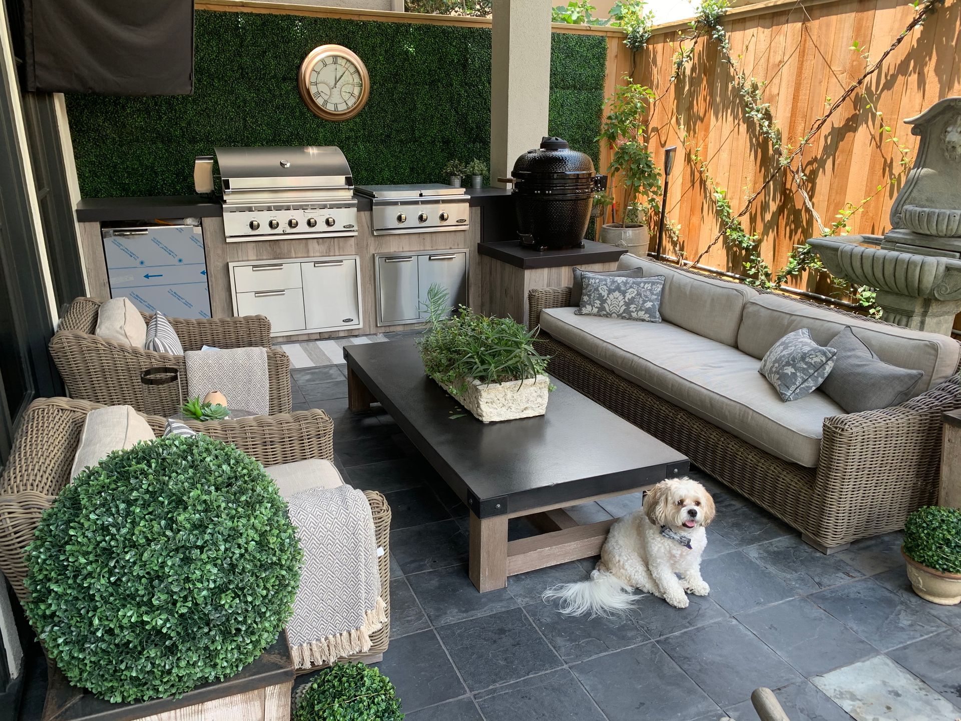 Outdoor patio with a grill station, seating, and a small dog.