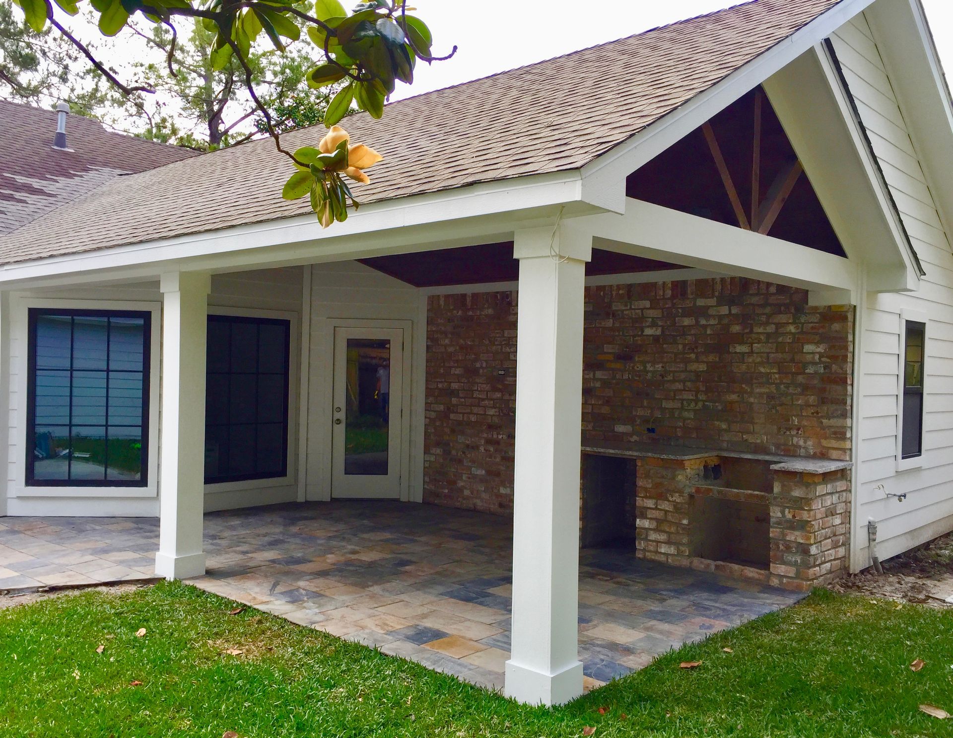 Covered patio with brick wall and columns; tile floor.