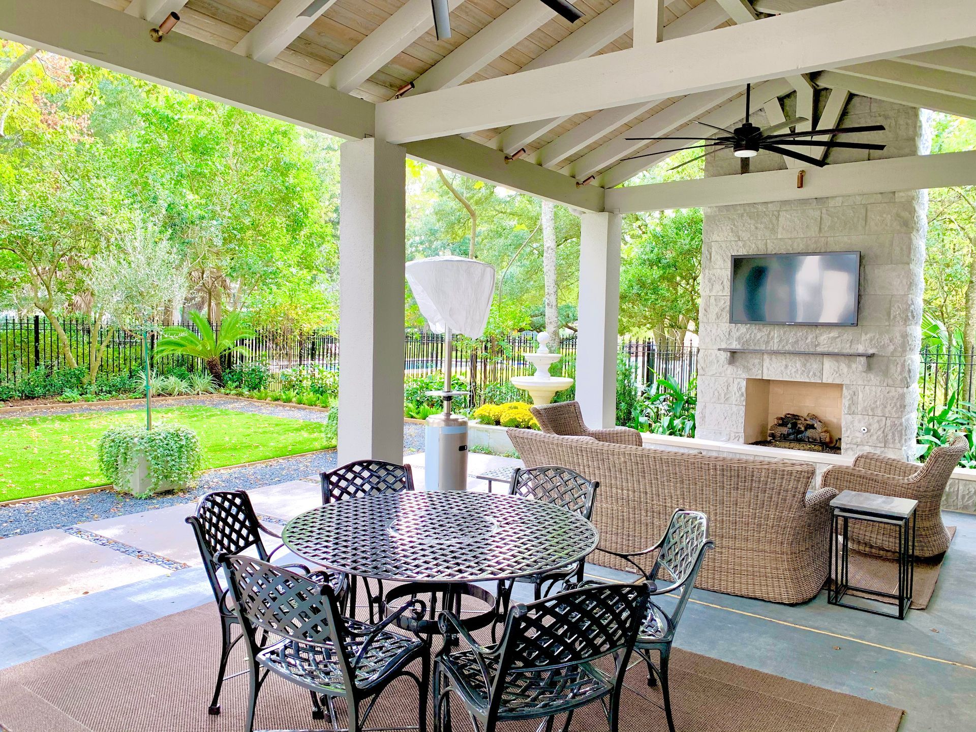 Outdoor covered patio with a dining table, seating, and a fireplace.