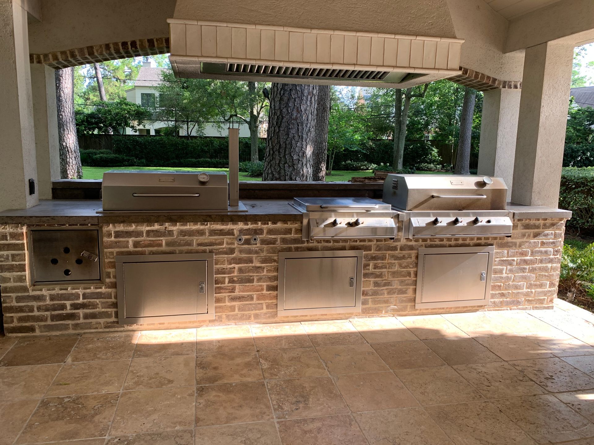 Outdoor kitchen with brick facade and stainless steel appliances.