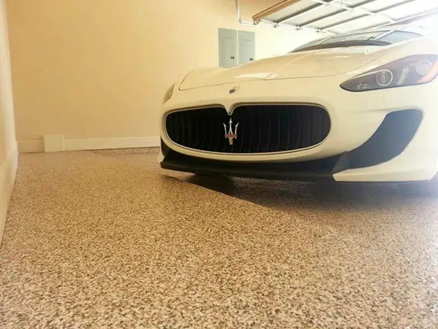 White Maserati parked in a garage with a speckled epoxy floor.