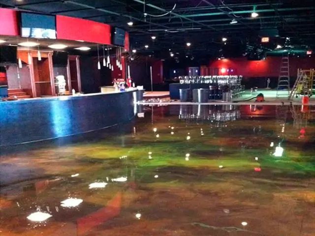 Interior of a flooded nightclub, reflective floor, red and black decor, empty bar.