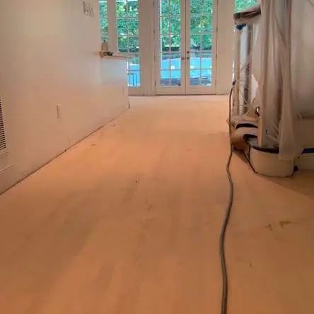 Wooden floor being refinished with doors and a wall in the background.