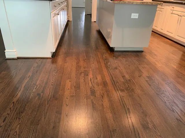 Dark stained hardwood floors in a kitchen with white cabinets and a kitchen island.