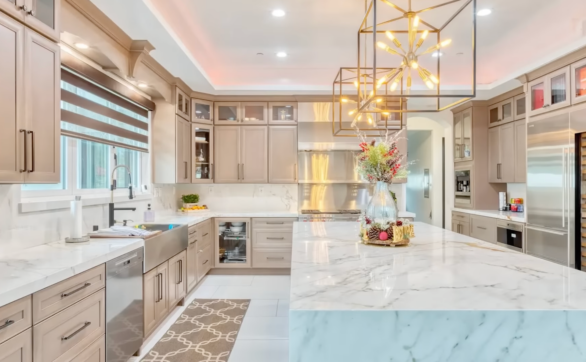 Bright modern kitchen with white cabinets, marble island, gold pendant lights, and stainless appliances