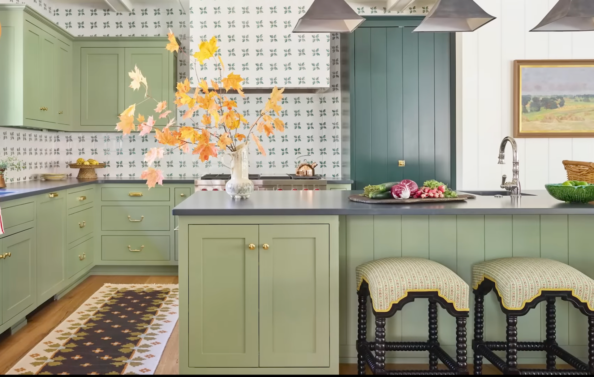 Mint green kitchen with black island, patterned backsplash, pendant lights, and floral arrangement