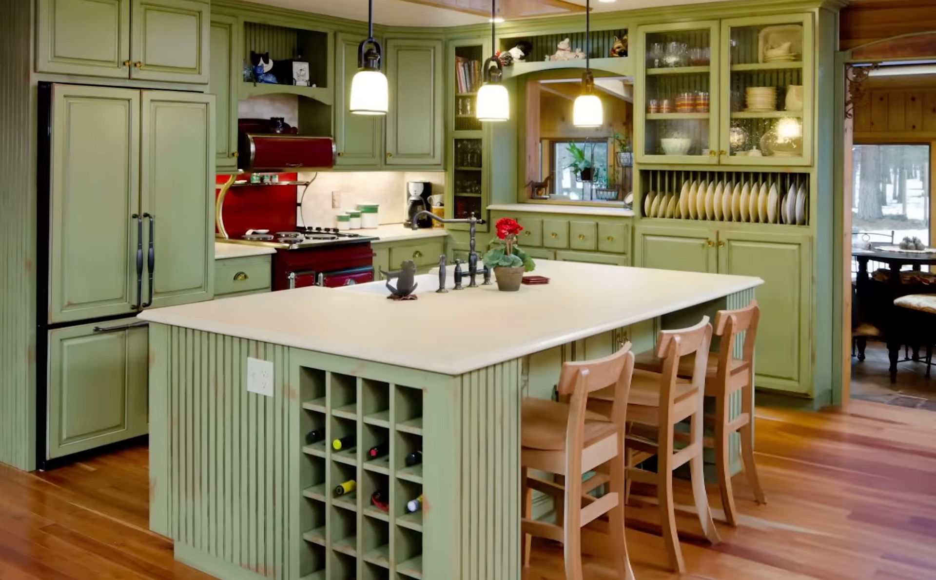 Bright green kitchen with a white island, wooden stools, and a large refrigerator.
