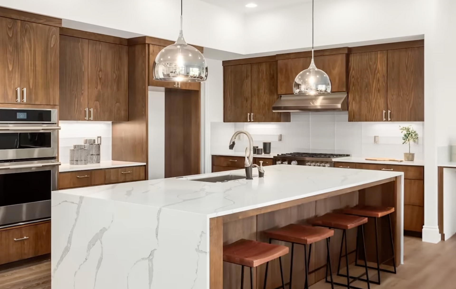 Modern kitchen with large white marble island, wood cabinets, and pendant lights