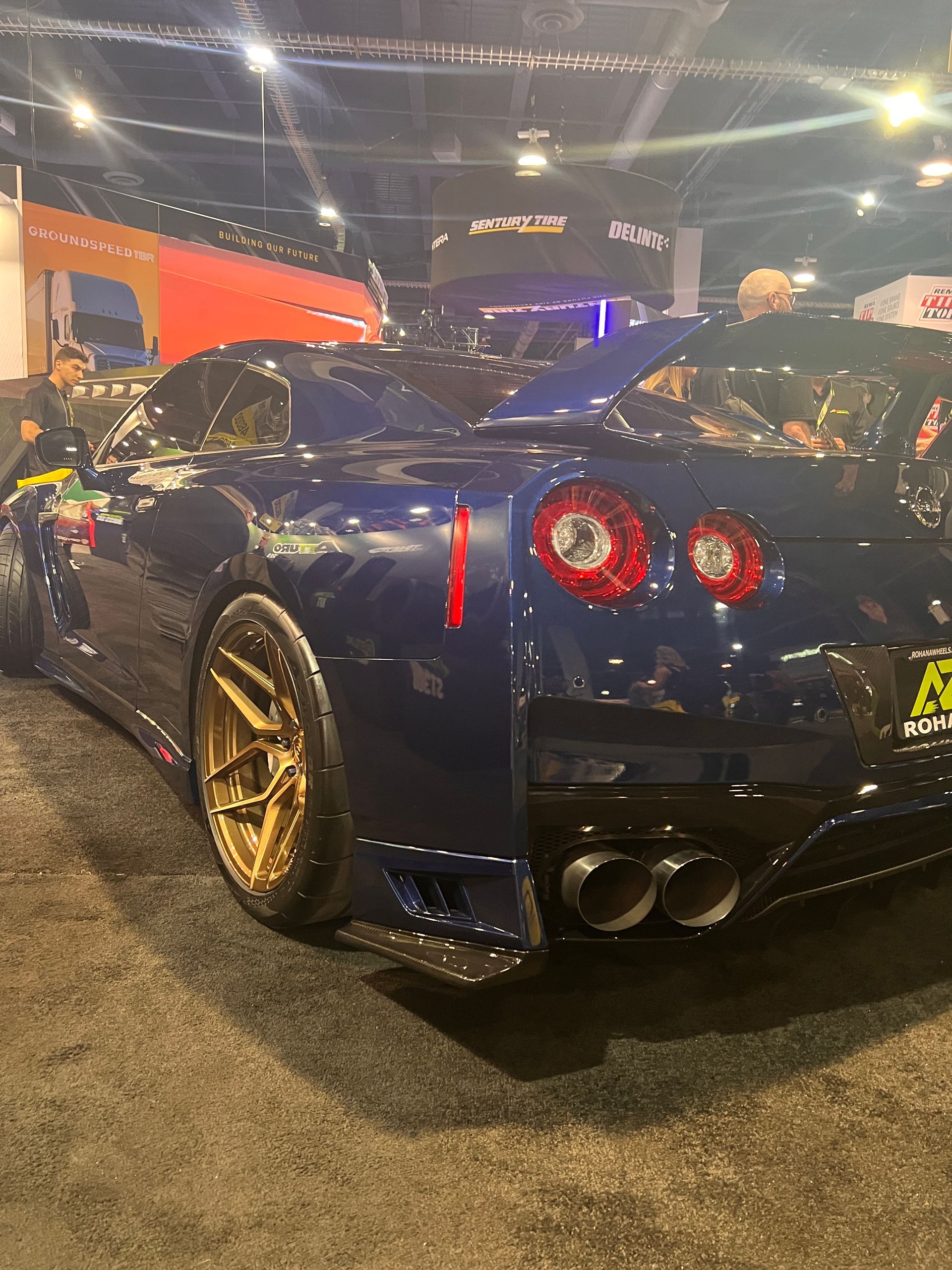 A blue sports car is parked at a car show.