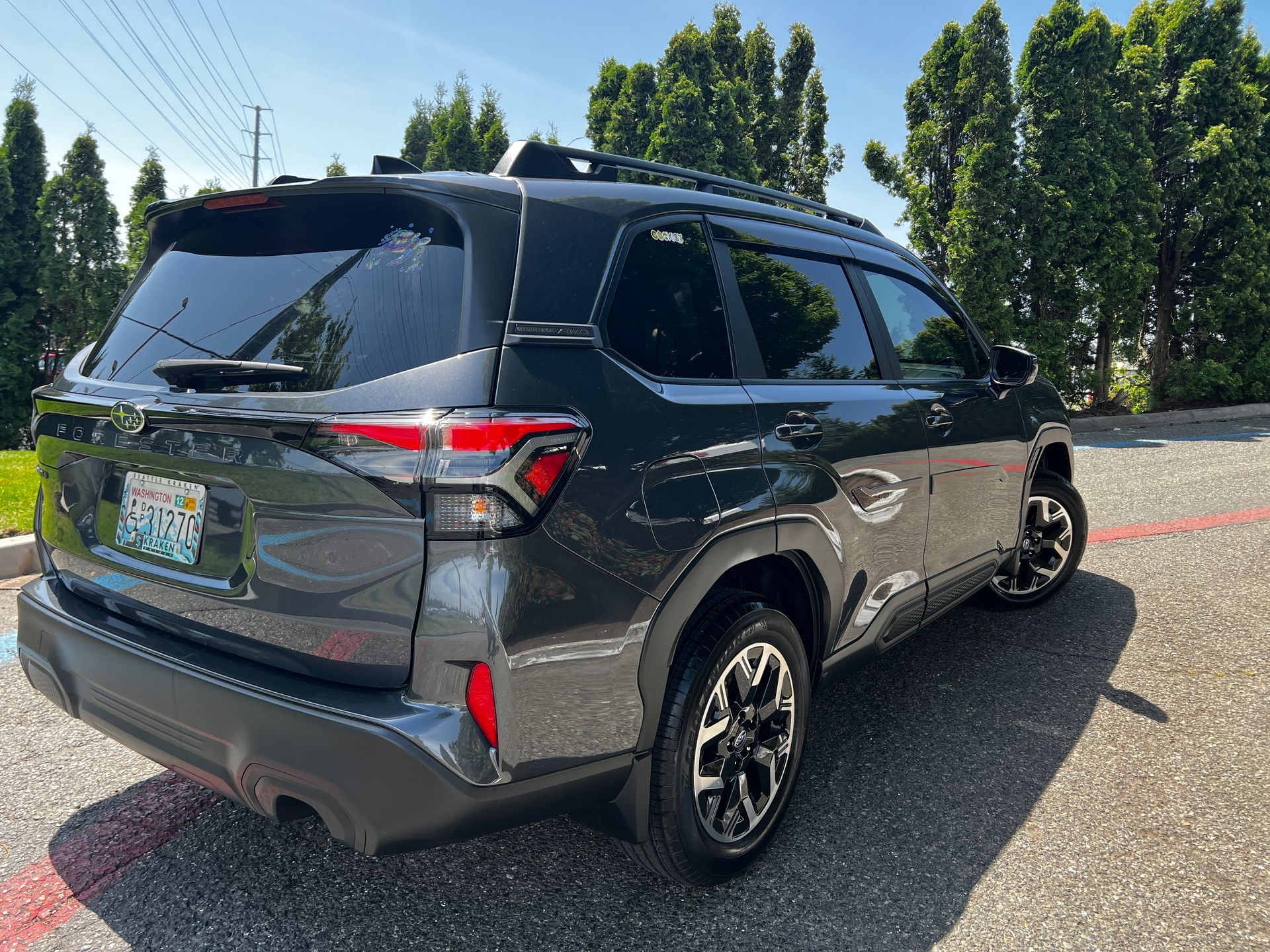 Dark gray crossover SUV parked on a paved lot, with tinted windows, sunny day.