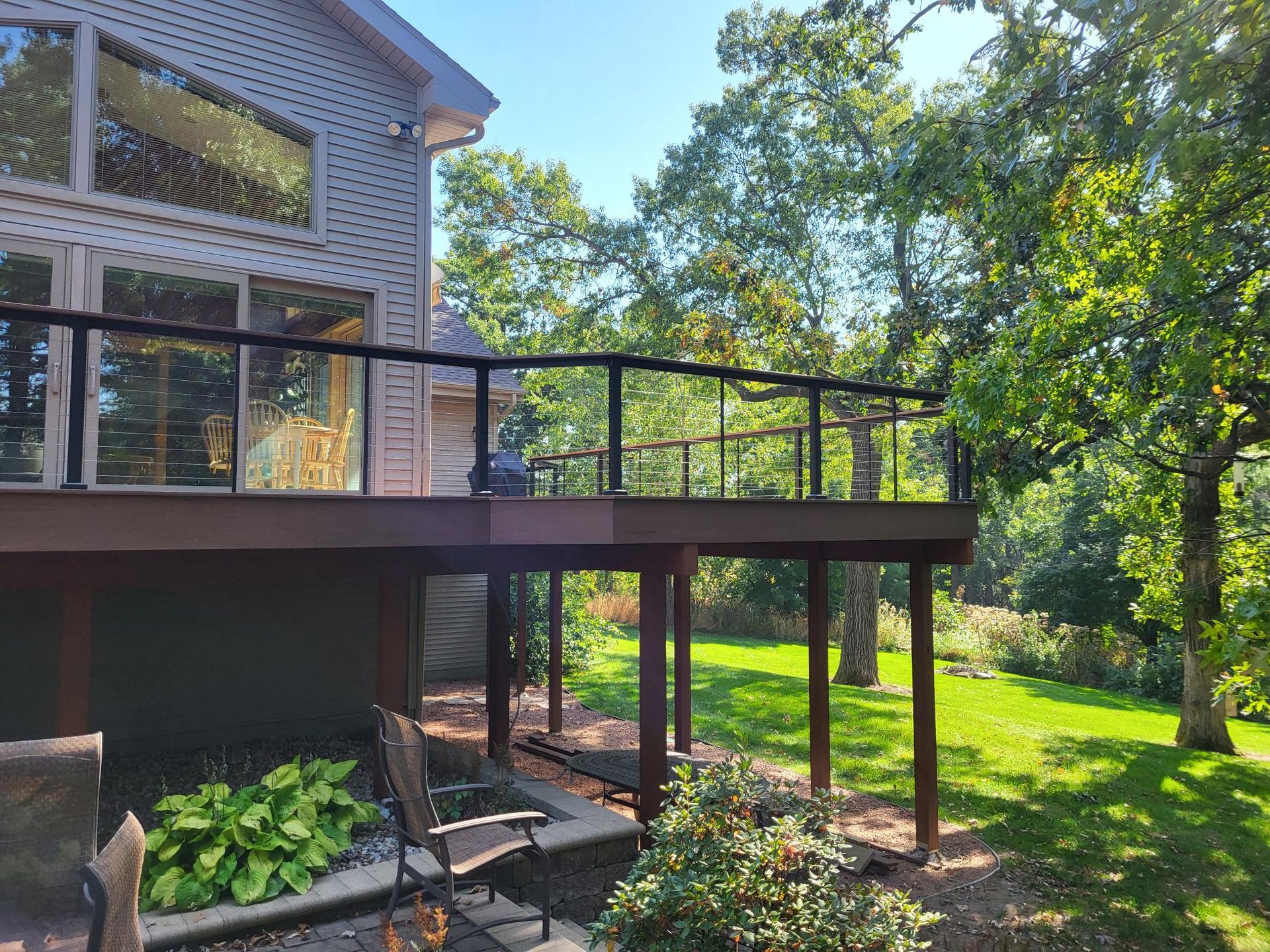 A deck with chairs and a table next to a swimming pool.