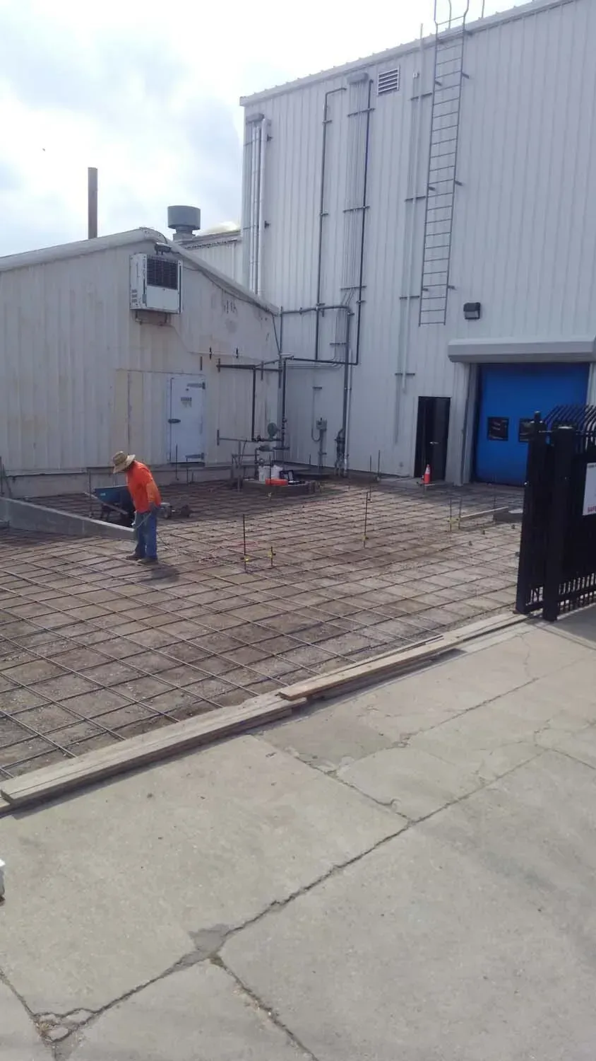 Construction worker near building with a gray ground and concrete surrounding.