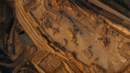Aerial view of a brown construction site with dirt roads, equipment, and pools of water.