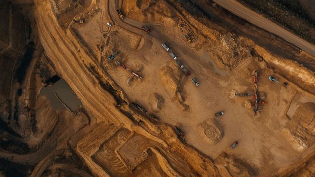 Aerial view of a brown construction site with dirt roads, equipment, and pools of water.