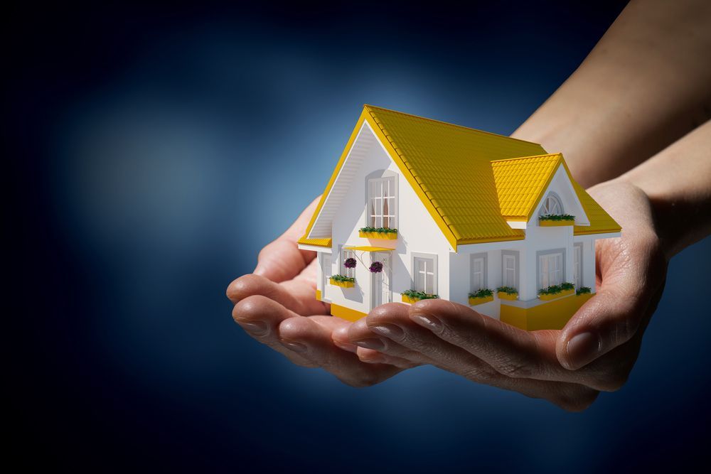 A Person Is Holding a Model House in Their Hands — Pink Conveyancing Services in Port Macquarie, NSW