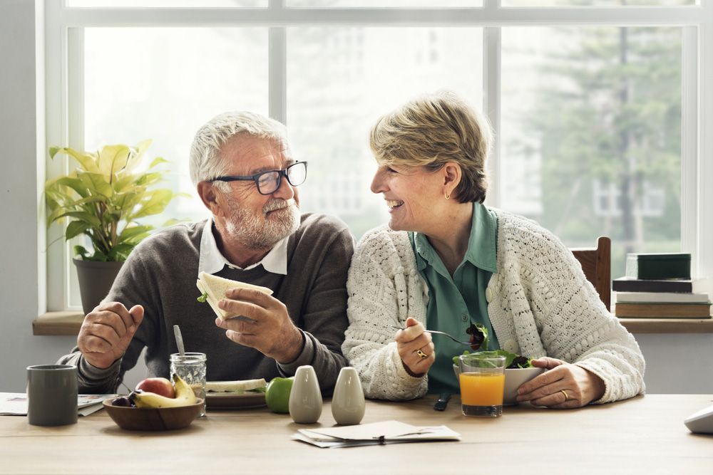 Retirees Sitting at A Table Eating Food — Pink Conveyancing Services in Port Macquarie, NSW