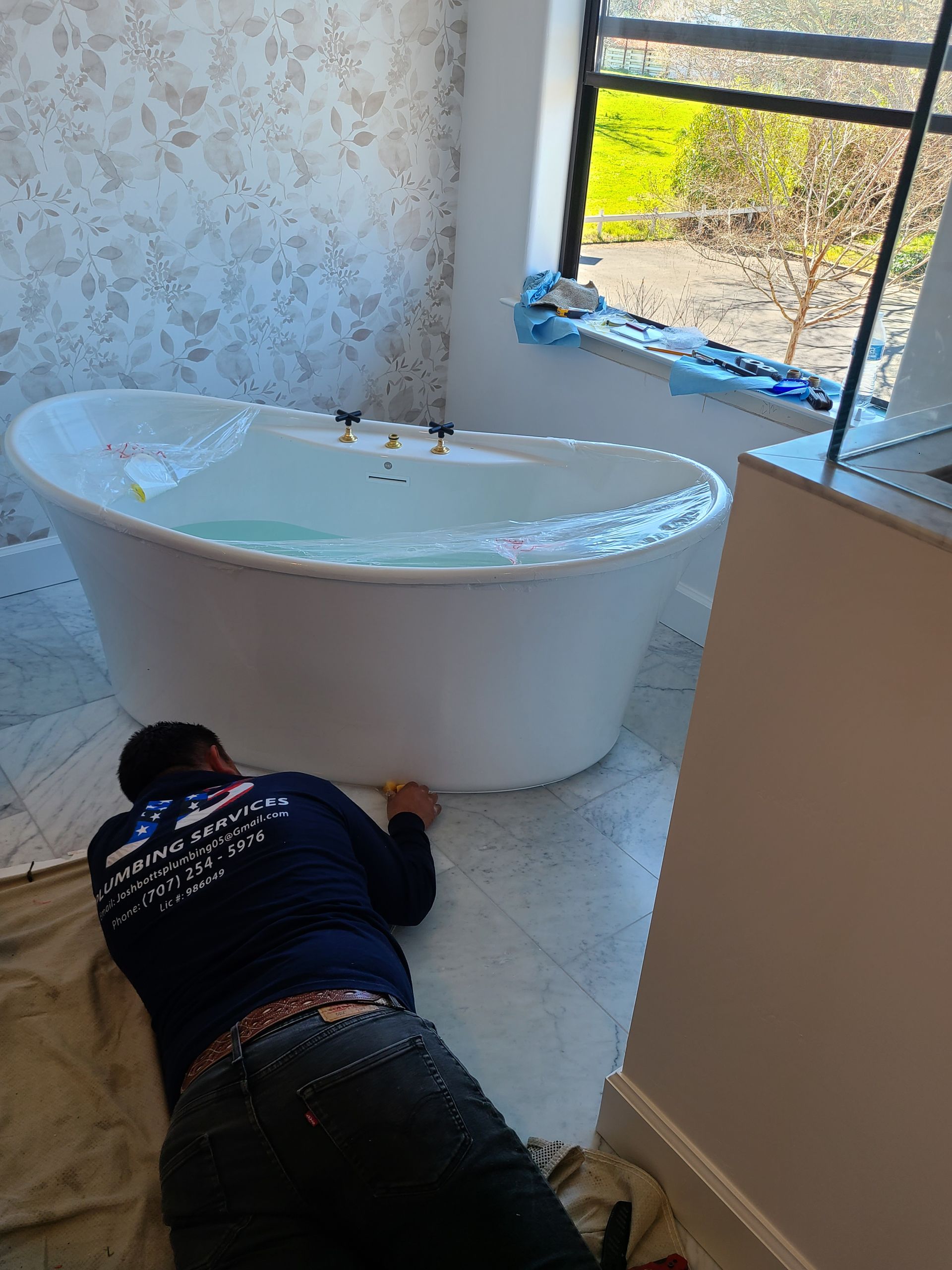 A plumber is fixing a sink in a kitchen.