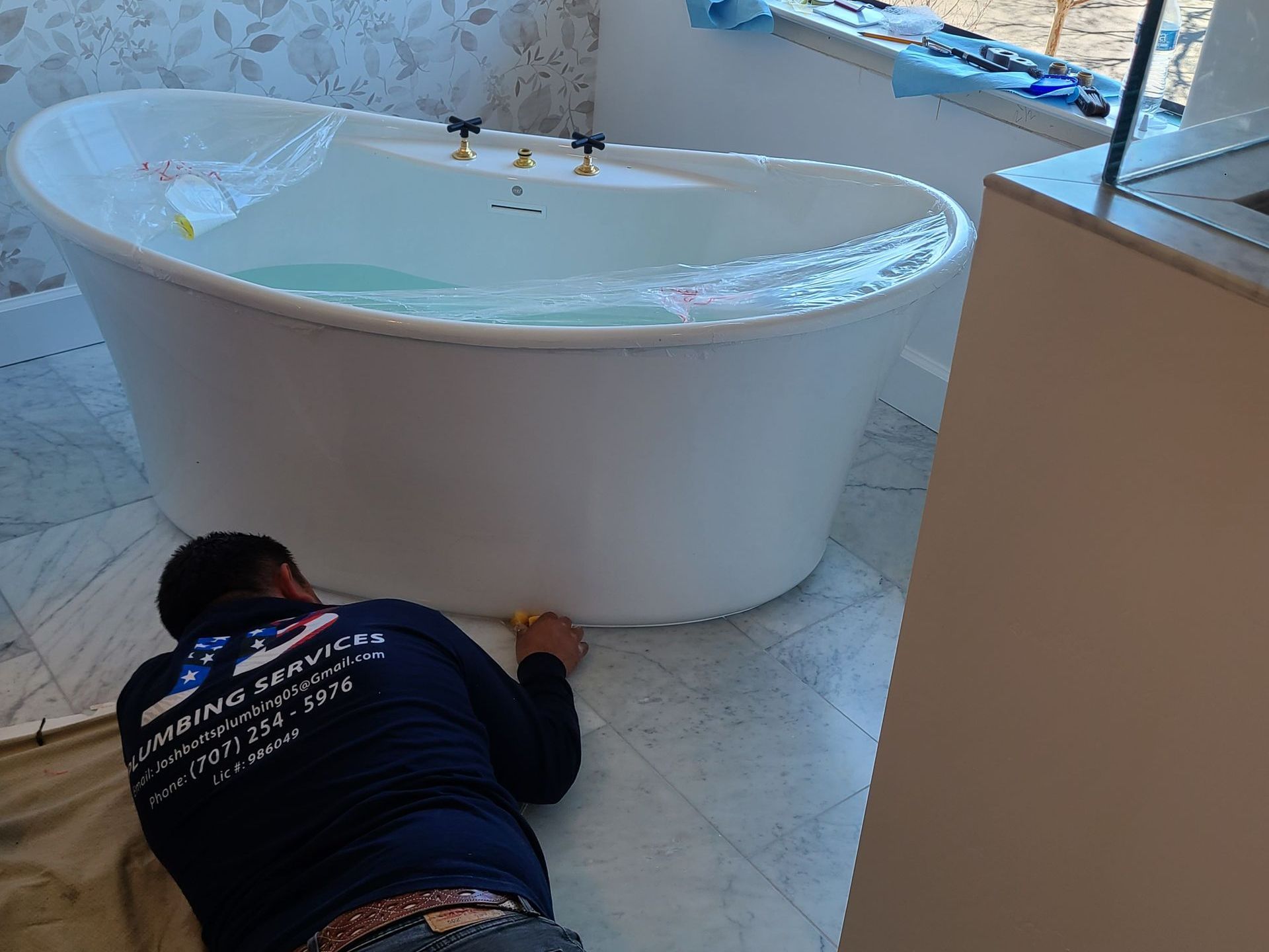 A plumber is fixing a sink pipe with a wrench.