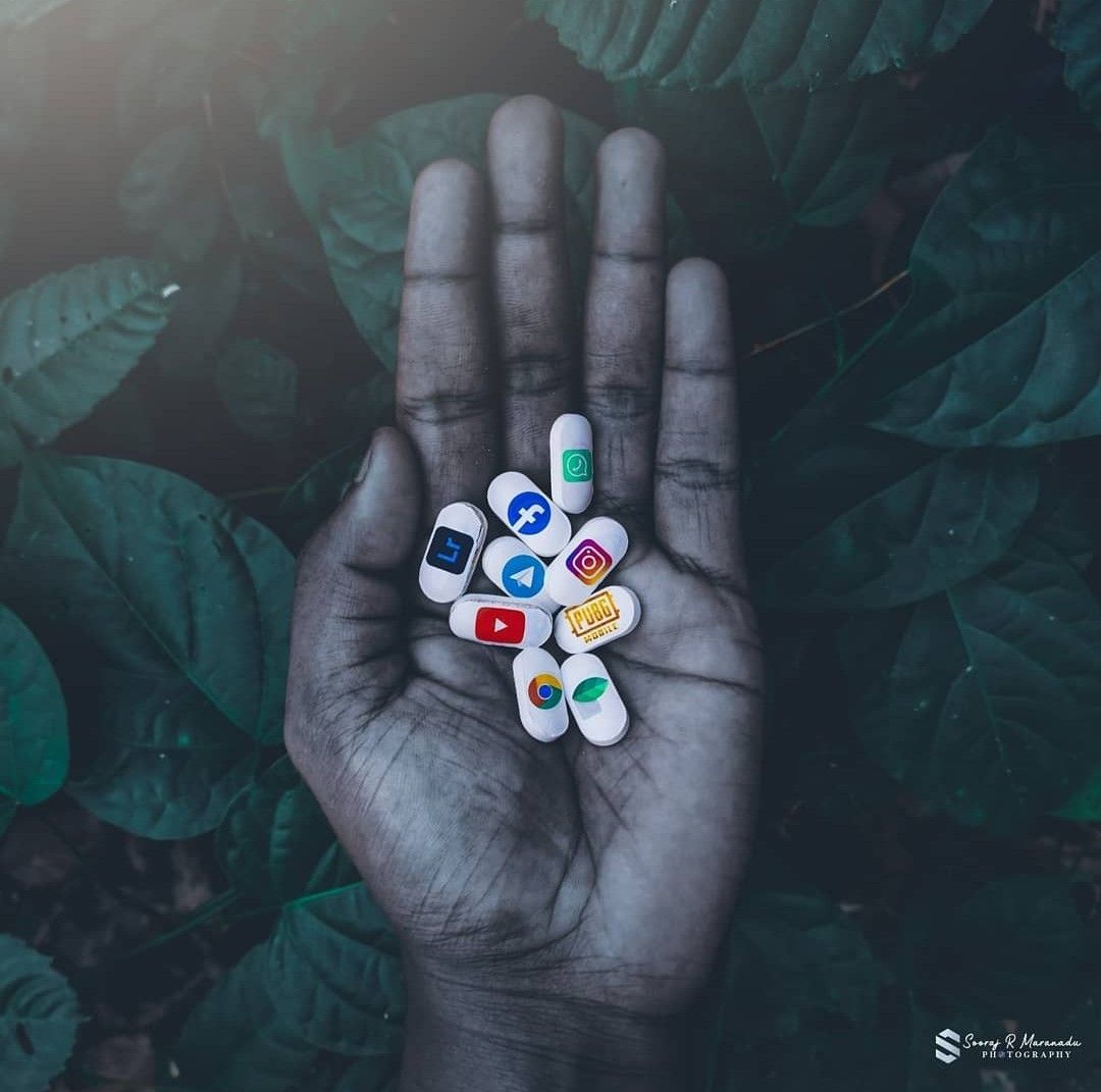 Mão segurando ícones de redes sociais representando o consumo digital e seu impacto na saúde mental.