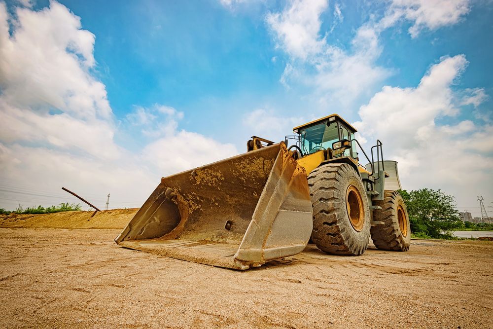 A Man is Driving a Yellow Tractor in a Dirt Field — Advanced Industry Training In South Townsville, QLD