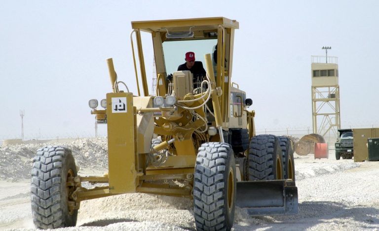 A Man is Driving a Bulldozer on a Dirt Road — Advanced Industry Training In South Townsville, QLD