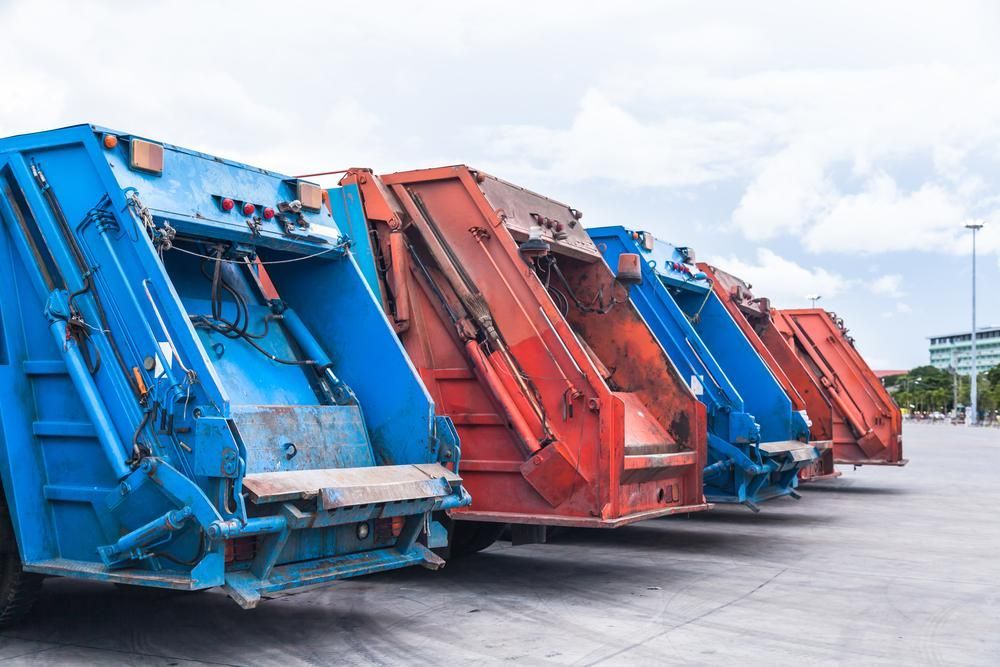 A Row of Blue and Red Garbage Trucks Are Parked in a Parking Lot — Advanced Industry Training In South Townsville, QLD