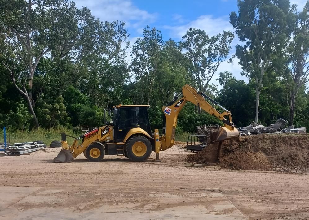 A Yellow Backhoe is Sitting in a Dirt Field Next to a Pile of Dirt — Advanced Industry Training In South Townsville, QLD