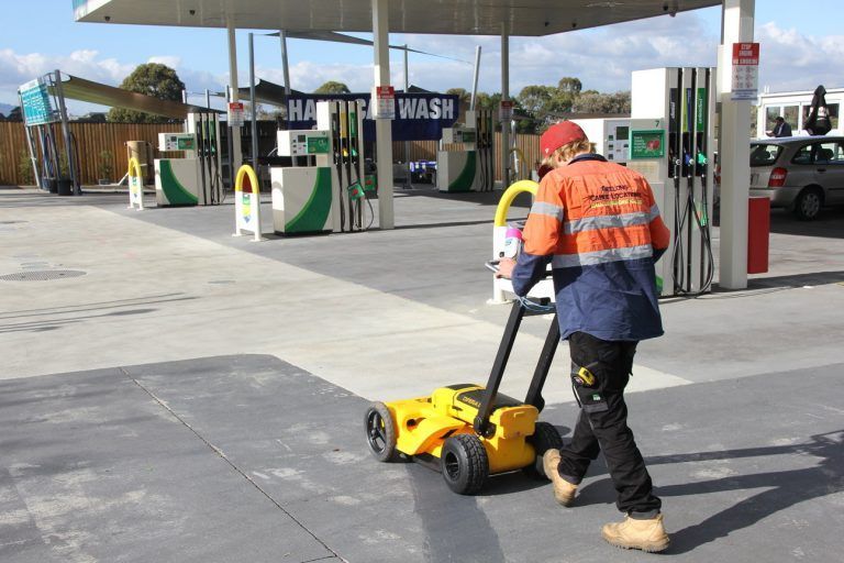 A Man is Pushing a Yellow Lawn Mower in Front of a Gas Station — Advanced Industry Training In South Townsville, QLD